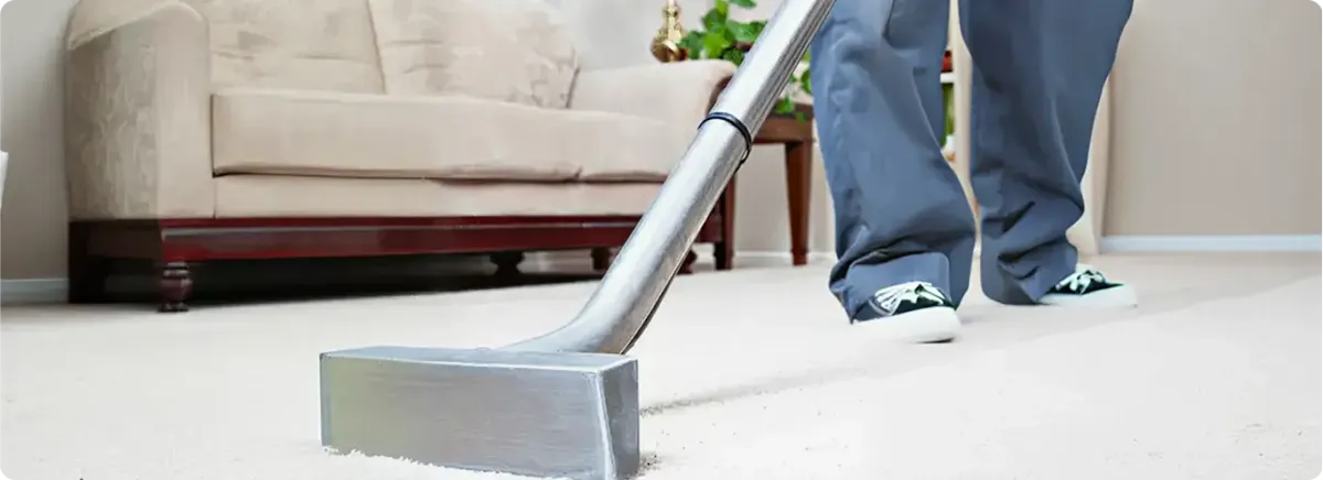 Carpet cleaning technician using a hot-water extraction wand on a light-colored carpet in a living room, Madison, WI.