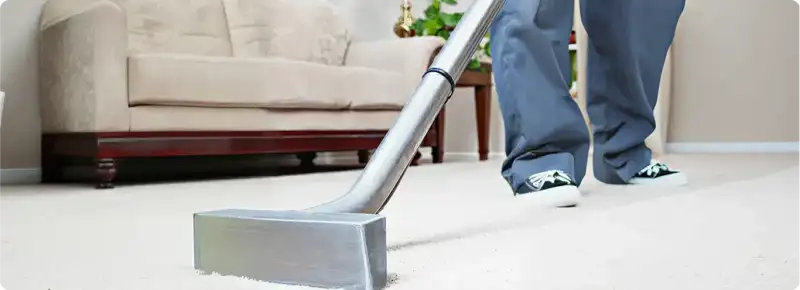 Carpet cleaning technician using a hot-water extraction wand on a light-colored carpet in a living room, Madison, WI.